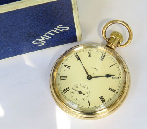 fig 1. A 1940s Smiths open-face pocket watch with a gold-tone metal case, white Roman numeral dial, and an accompanying textured blue presentation box.