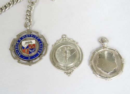 fig 2. An Edwardian sterling silver curb link watch chain featuring a T-bar, swivel clasp, and an enamel medallion fob accompanied by two silver sporting medals.