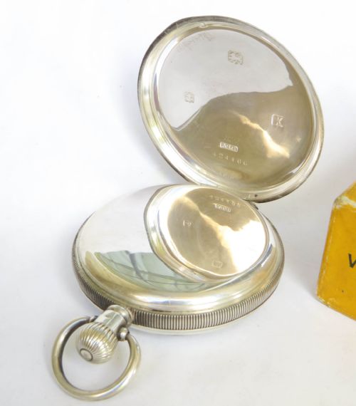fig 1. An antique 1922 open-face silver pocket watch featuring a white enamel dial with Roman numerals alongside its original yellow Dennison box.