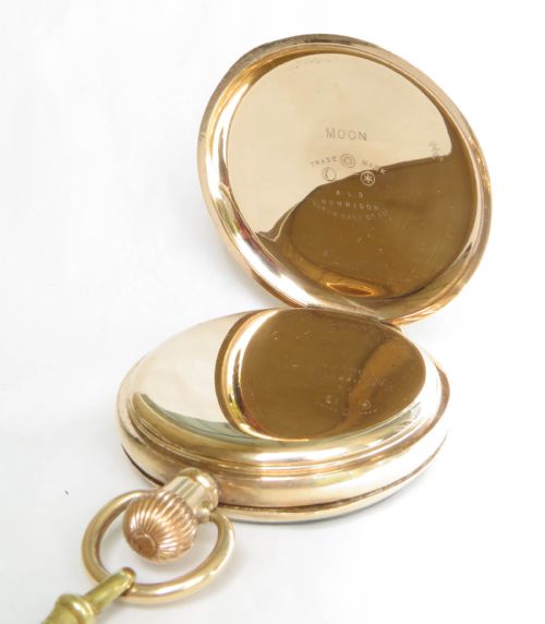 fig 1. An antique 1920s gold-plated open-face pocket watch by Syren featuring a white enamel dial with Roman numerals, a sub-seconds dial, and an attached curb link chain with a tassel fob.