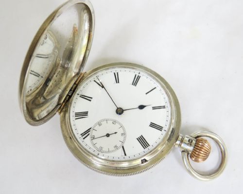fig 1. A silver full hunter pocket watch shown open to display a white enamel dial with black Roman numerals and a small seconds sub-dial.