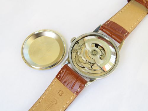 fig 1. A 1950s Eterna-Matic gents wrist watch featuring a champagne dial, gold-tone hour markers, date aperture, and a brown leather strap.