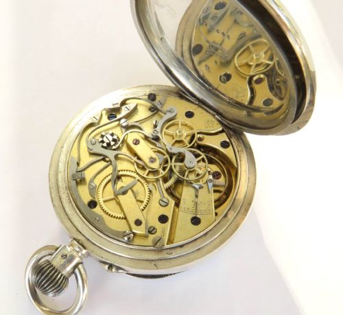 fig 3. An antique open-faced silver chronograph pocket watch featuring a white enamel dial with Roman numerals and dual sub-dials.