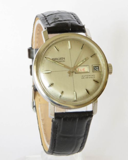 fig 1. A 1960s gents Gruen Precision Auto-Wind wrist watch with a silver dial, day-date window, and black leather strap.