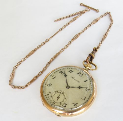 fig 1. An open-face 1930s gold-tone pocket watch displaying a patterned cream dial with black Arabic numerals, a sub-seconds dial, and a linked chain.