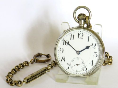 fig 1. An antique silver-tone Octava 8-day open-face pocket watch featuring a white enamel dial with black Arabic numerals and an attached chain.