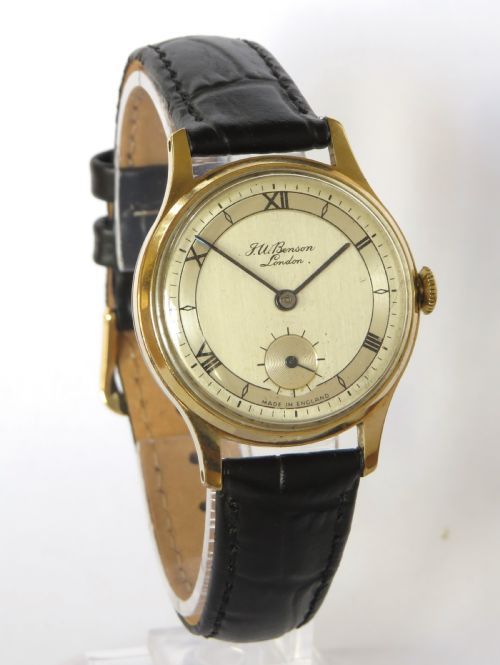 fig 1. A 1950s circular gold-plated wristwatch featuring a cream dial, black Roman numerals, subsidiary seconds dial, and a black leather strap.