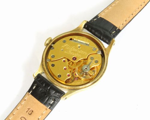 fig 2. A 1950s circular gold-plated wristwatch featuring a cream dial, black Roman numerals, subsidiary seconds dial, and a black leather strap.