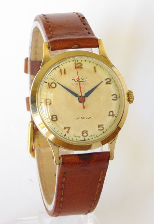 fig 1. A 1960s gents 9ct gold Rone Seventeen wristwatch featuring a champagne dial with gold Arabic numerals and a brown leather strap.