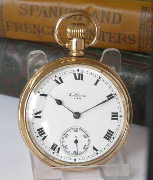 fig 1. An open-face antique gold-tone pocket watch featuring a white enamel dial with black Roman numerals and a subsidiary seconds sub-dial.