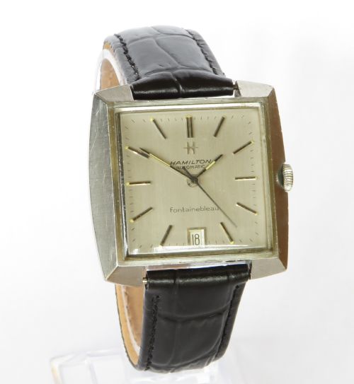 fig 1. A vintage Hamilton Fontainebleau automatic wristwatch featuring a square silver-toned case, champagne dial with hour markers, a date window at six oclock, and a black textured leather strap.