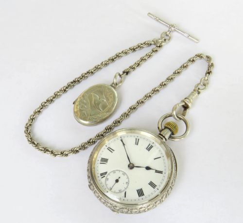 fig 1. An antique open-face silver pocket watch with a white enamel dial and Roman numerals, attached to a silver rope-twist Albert chain with a T-bar and engraved pendant.