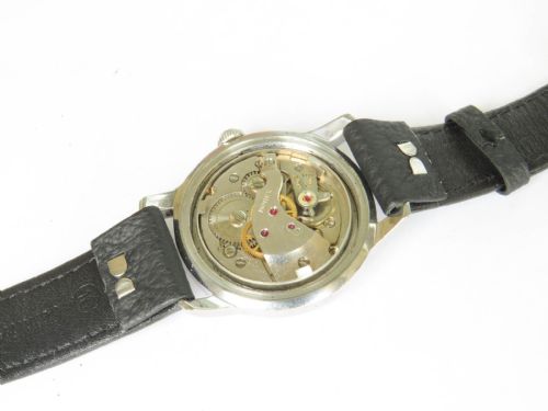fig 2. A 1950s gents wristwatch featuring a round stainless steel case, an off-white dial with silver-tone hour markers, and a black textured leather strap.