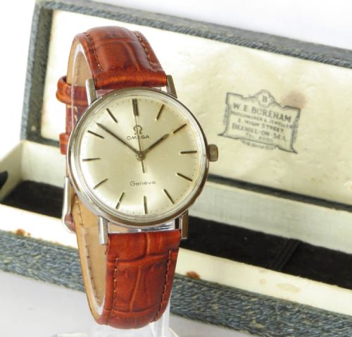 fig 1. A 1966 Omega Geneve wristwatch featuring a round silver-toned dial, black baton indices, and a textured brown leather strap.