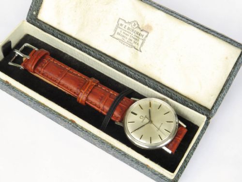 fig 2. A 1966 Omega Geneve wristwatch featuring a round silver-toned dial, black baton indices, and a textured brown leather strap.