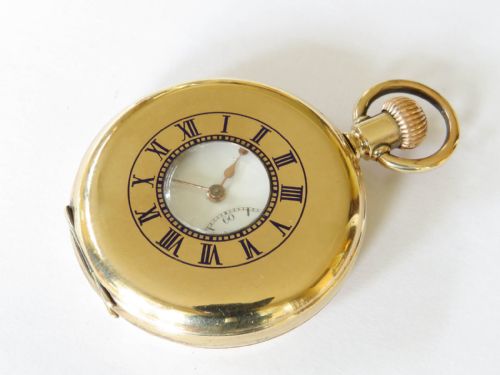 fig 1. An opened gold-toned half hunter pocket watch featuring a white enamel dial, black Roman numerals, and a sub-seconds dial.