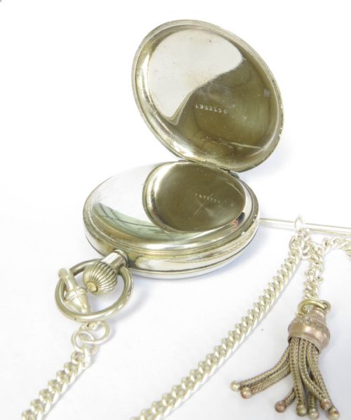 fig 2. An open-face silver-toned pocket watch featuring a white enamel dial, black Roman numerals, a sub-seconds dial, and an attached curb link chain with a tassel fob.