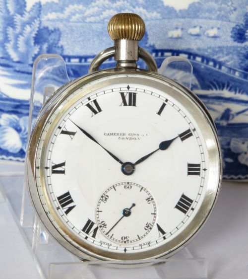 fig 1. An open-face antique silver pocket watch featuring a white enamel dial with black Roman numerals and a subsidiary seconds sub-dial.