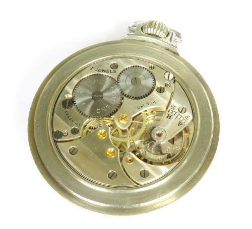 fig 2. An open-face pocket watch featuring a white enamel dial with black Roman numerals, blued steel hands, a subsidiary seconds dial, and a silver-toned metal case with a gold-coloured winding crown.