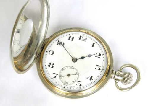 fig 1. A 1930s silver hunter pocket watch featuring a open hinged cover, a white enamel dial with black Arabic numerals, and a sub-seconds display at six oclock.