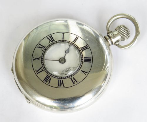 fig 2. A 1930s silver hunter pocket watch featuring a open hinged cover, a white enamel dial with black Arabic numerals, and a sub-seconds display at six oclock.