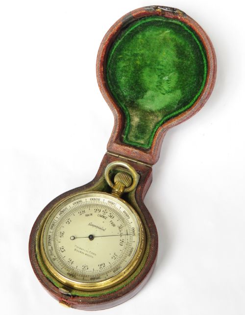 fig 1. An antique brass pocket barometer and altimeter shown inside an open burgundy leather travel case lined with green velvet.
