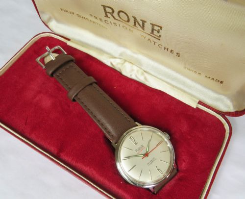 fig 1. A 1960s mens Rone automatic wristwatch featuring a champagne dial, gold-tone casing, and a brown leather strap.