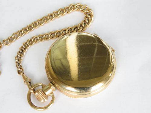 fig 2. An antique gold-coloured full hunter pocket watch open to reveal a white dial with Roman numerals, alongside a curb link chain and decorative shield fob.