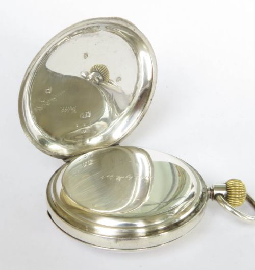 fig 3. An antique silver half-hunter pocket watch featuring an outer case with blue Roman numerals and a central dial marked Hamilton and Inches Edinburgh.