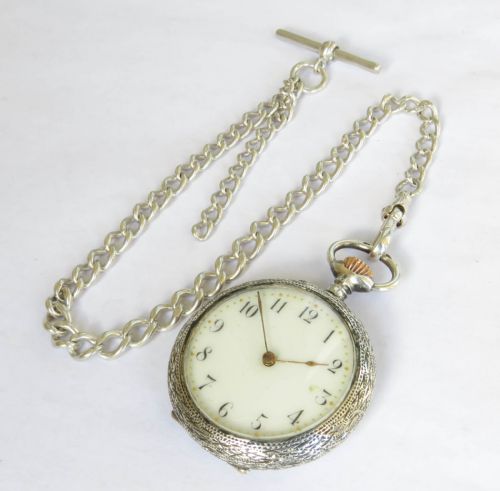 fig 1. An antique sterling silver fob watch featuring an engraved case and white enamel dial alongside a silver curb-link Albert chain with a T-bar.