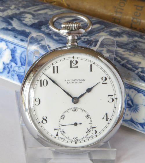 fig 1. A 1940s silver-toned open-face pocket watch featuring a white enamel dial signed J W Benson London with black Arabic numerals and a subsidiary seconds dial.