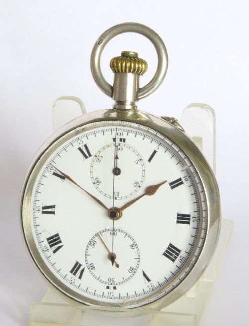 fig 1. An open-face antique silver chronograph pocket watch featuring a white enamel dial with black Roman numerals, two subsidiary dials, and a gold-toned winding crown.
