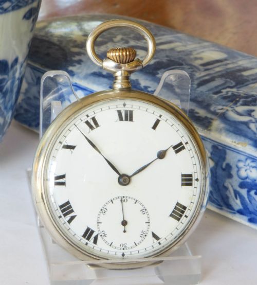 fig 1. An open-face antique Swiss silver pocket watch featuring a white enamel dial with black Roman numerals and a subsidiary seconds sub-dial.