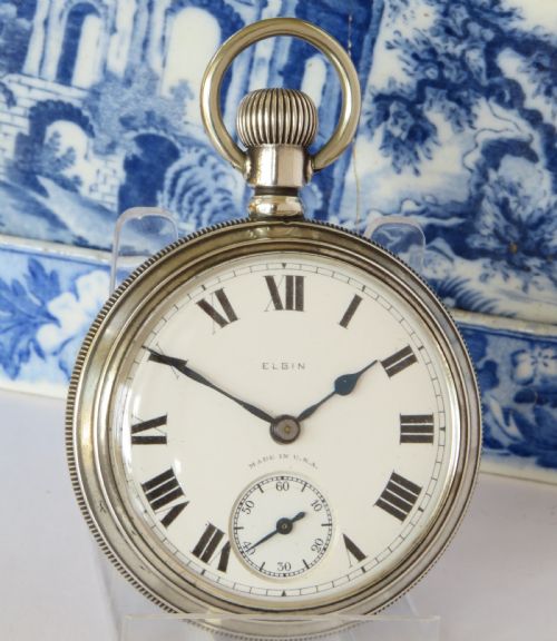 fig 1. An antique open-face silver pocket watch with a white dial featuring Roman numerals, spade hands, and a subsidiary seconds dial.