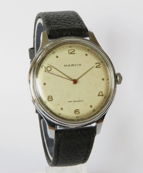 fig 1. A 1950s gents Marvin wrist watch featuring a cream dial with Arabic numerals, a stainless steel case, and a textured black leather strap.