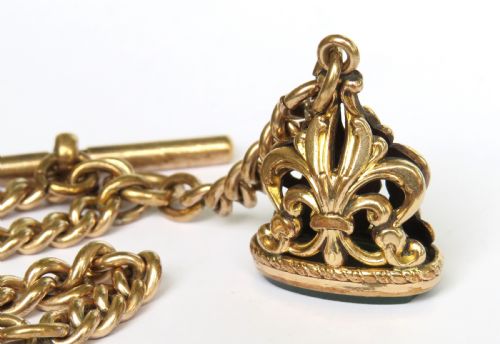 fig 1. An antique rolled gold curb link Albert watch chain featuring a T-bar, swivel clasp, bolt ring, and a suspended fob with a green oval stone intaglio.