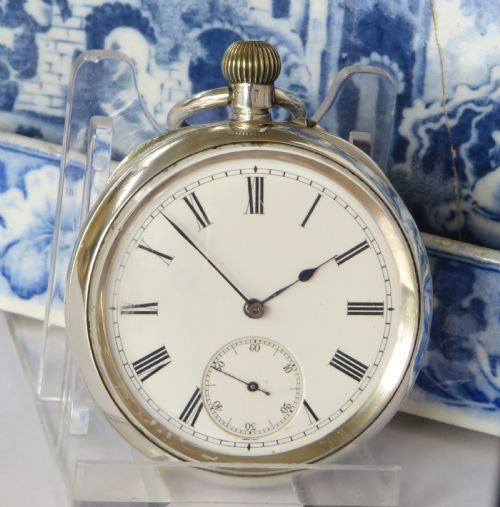 fig 1. An open-face antique silver pocket watch featuring a white enamel dial with black Roman numerals and a subsidiary seconds dial.