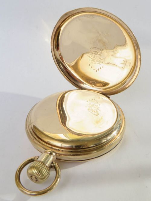 fig 2. A 1930s gold full hunter pocket watch shown open to display a white enamel dial with Roman numerals and a subsidiary seconds dial.
