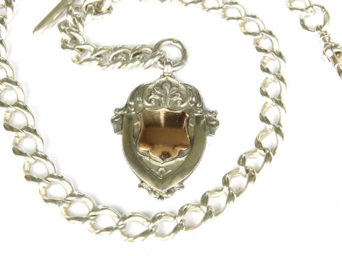 fig 1. A Victorian sterling silver Albert pocket watch chain featuring graduated curb links, a T-bar, swivel clasp, and a shield fob with rose gold detailing.