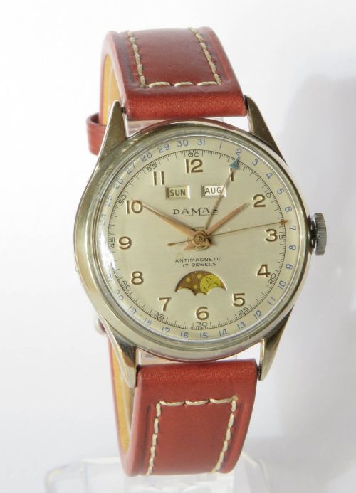 fig 1. A 1950s Damas gents wrist watch featuring a cream dial with day, month, pointer date, and moonphase complications on a brown leather strap.
