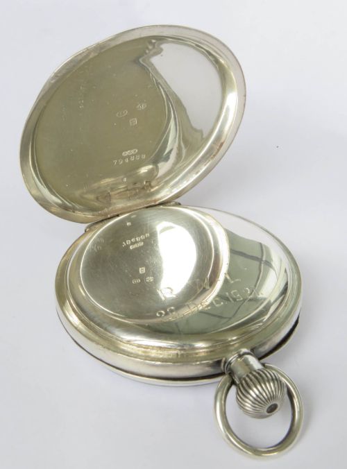 fig 2. An open-face silver pocket watch displaying a white enamel dial with black Roman numerals and a subsidiary seconds sub-dial.