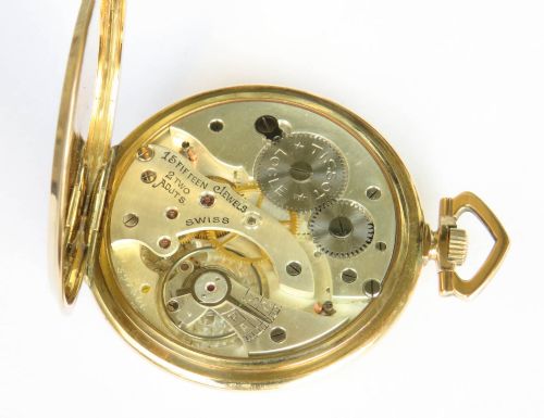 fig 2. An open-face Art Deco pocket watch featuring a gold case, champagne dial with stylized Arabic numerals, sub-seconds dial, and geometric top bow.