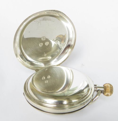 fig 2. An antique sterling silver half hunter pocket watch featuring an engine-turned case with blue enamel Roman numerals around a central aperture.