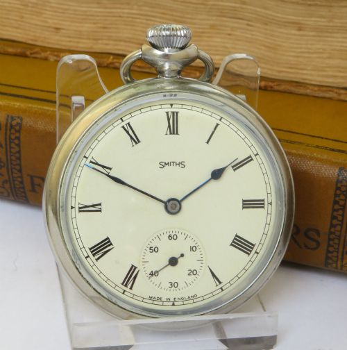fig 1. An open-face 1950s Smiths pocket watch featuring a silver-tone chrome case, cream dial with black Roman numerals, and a subsidiary seconds sub-dial.