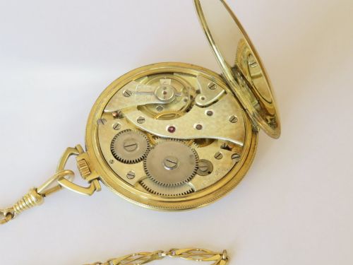 fig 1. An Art Deco gold-plated open-face pocket watch featuring a geometric patterned dial, Arabic numerals, sub-seconds dial, and attached gold-plated chain.