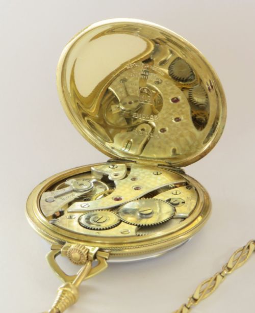 fig 2. An Art Deco gold-plated open-face pocket watch featuring a geometric patterned dial, Arabic numerals, sub-seconds dial, and attached gold-plated chain.