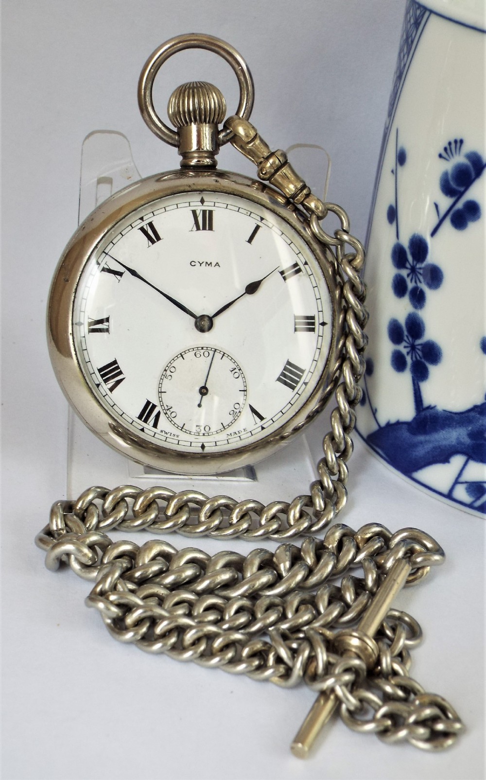 A 1920s Cyma pocket watch with chain.