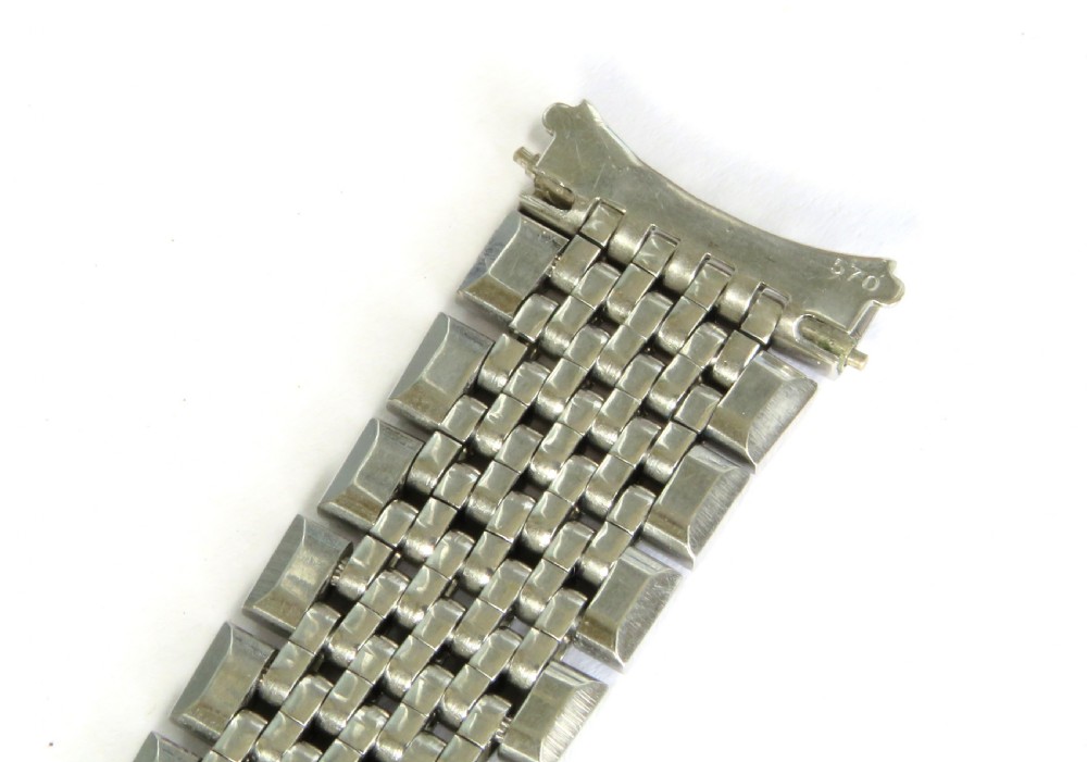 An overhead view of a segmented stainless steel Omega watch bracelet with a branded clasp against a neutral background. View V