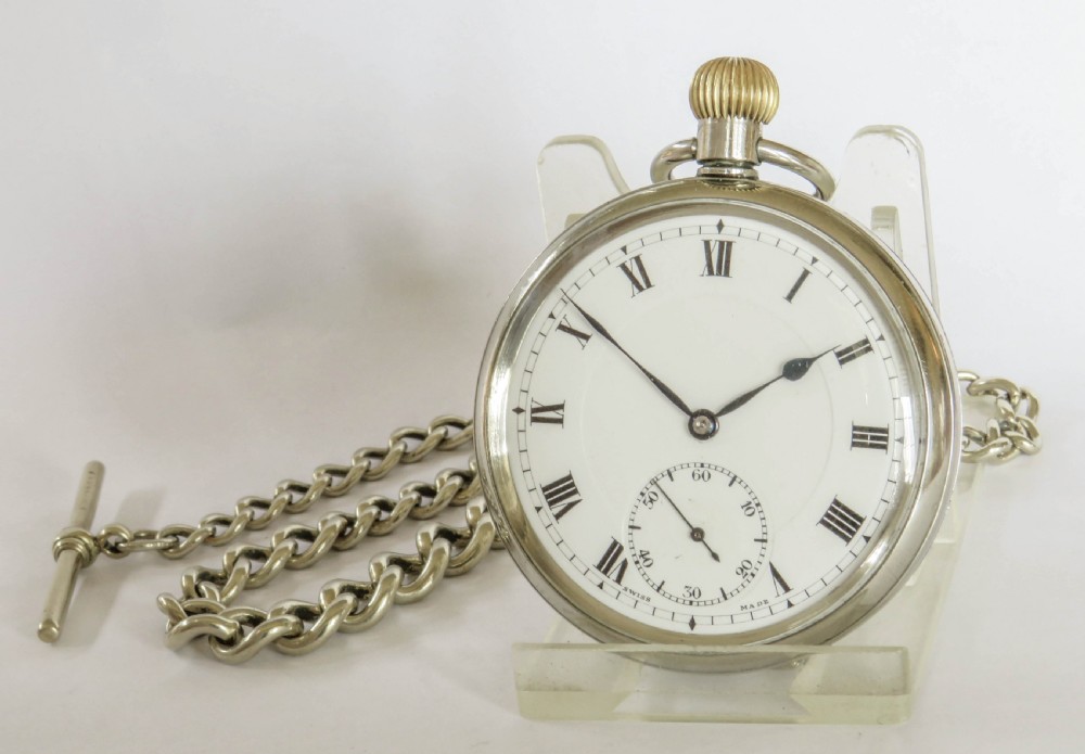 An open-face 1930s Doxa pocket watch with a white enamel dial, black Roman numerals, sub-seconds dial, and attached silver-toned Albert chain.