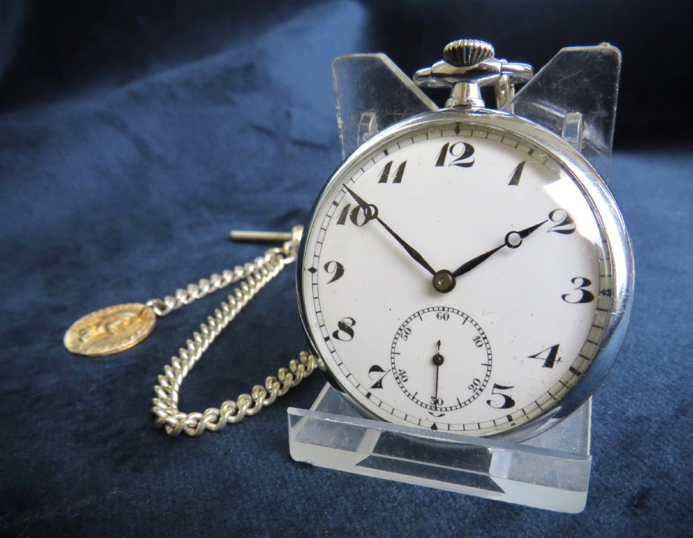 A 1930s open-face Cyma pocket watch featuring a white dial with black Arabic numerals, sub-seconds dial, and attached curb chain with T-bar.